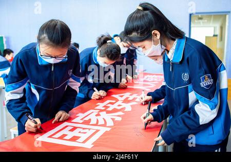 HOHHOT, CINA - 15 APRILE 2022 - gli studenti firmano i loro nomi su un banner con la scritta "ognuno è responsabile della sicurezza nazionale" a Hohhot, Mongol interno Foto Stock