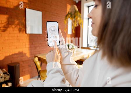 Donna che tiene il telefono con l'applicazione Smart Home in esecuzione Foto Stock