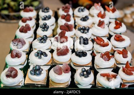 Meringa dessert Pavlova torta con frutti di bosco freschi su sfondo di pietra. Torta alla bacche Pavlova con mirtilli, fragole, lamponi e su un b scuro Foto Stock