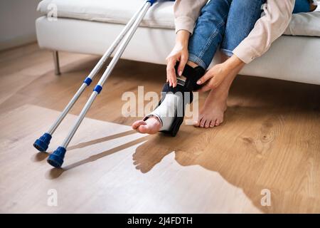 Donna con lesioni alle gambe utilizzando stampelle a casa Foto Stock