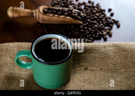 Tazza di caffè verde con chicchi di caffè su sfondo di legno Foto Stock
