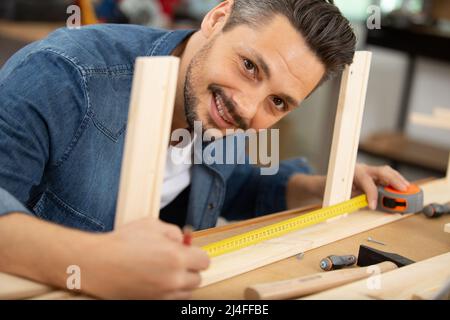 primo piano dell'uomo che misura pavimenti in legno Foto Stock