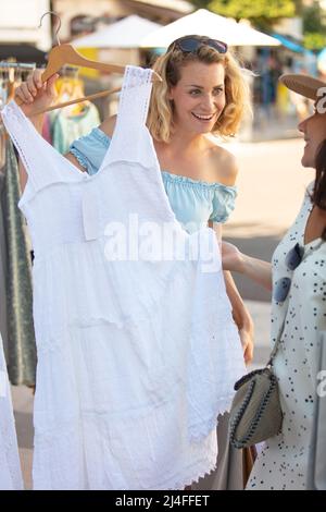 giovani donne sorridenti che scelgono i vestiti in negozio Foto Stock