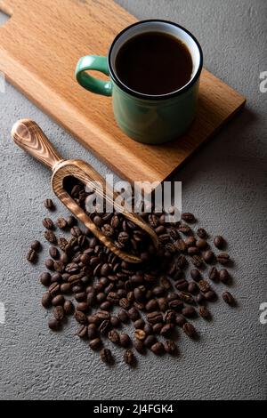 Tazza di caffè verde con chicchi di caffè su sfondo di cemento Foto Stock