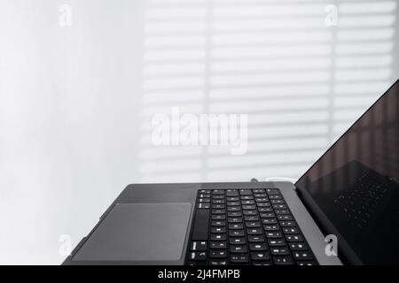 Vista laterale ritagliata del computer portatile in un'area di lavoro moderna e leggera. Lavoro o ufficio domestico di programmatore o freelance. Lavoro in remoto online Foto Stock