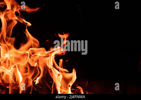 Bella fiamma arancione rosso fuoco isolato su sfondo nero. Lingue ardenti di falò di notte Foto Stock