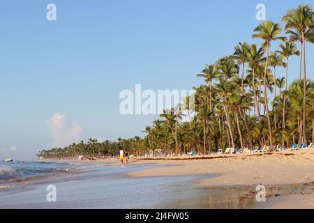 Vista sfocata sulle palme da cocco sulla spiaggia tropicale. Turisti sulla costa della Repubblica Dominicana al mattino Foto Stock