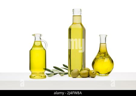 Bottiglie di olio d'oliva di varietà con olive verdi su ripiano bianco Foto Stock