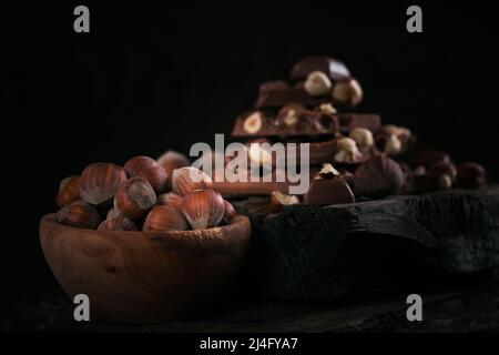 Mucchio di cioccolato al latte di nocciole e noci su sfondo scuro Foto Stock
