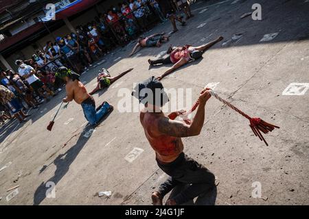 Navotas, Filippine. 15th Apr 2022. (NOTA DEI REDATTORI: L'immagine contiene contenuti grafici) i flagellanti mascherati con le spalle sanguinose si frustano durante i riti lenten del Venerdì Santo in Navotas. Molti cattolici filippini segnano la settimana Santa sottomettendosi a diverse forme di penitenza fisica nella speranza di essere perdonati per i loro peccati. (Foto di Oliver Haynes/SOPA Images/Sipa USA) Credit: Sipa USA/Alamy Live News Foto Stock