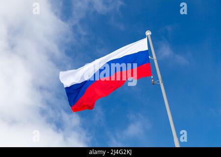 La bandiera nazionale della Russia, conosciuta anche come la bandiera di Stato della Federazione russa, è sotto il cielo azzurro in una giornata di sole Foto Stock