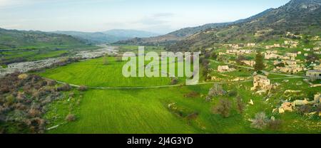 Panorama della valle del fiume Dhiarizos a Cipro con campi verdi e Souskiou villaggio abbandonato Foto Stock