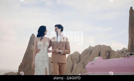 Un interessante scatto fotografico degli sposi novelli. Azione. La sposa di aspetto grazioso in uno stretto bel vestito bianco lungo con il suo carino Foto Stock