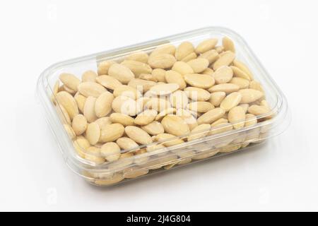 Impaccate le mandorle crude sbucciate su sfondo bianco. Mandorle crude pelate confezionate per la vendita al banco del mercato. Primo piano Foto Stock