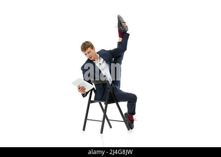 Ritratto di giovane bell'uomo, lavoratore di ufficio seduto su sedia da ufficio e utilizzando tablet isolato su sfondo bianco Foto Stock