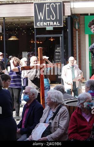 Redhill, Surrey, Regno Unito. 15th aprile 2022. Centinaia di cristiani provenienti da 20 chiese locali hanno preso le strade per celebrare il Venerdì Santo, con un servizio all'aperto nel centro della città. Tra un negozio di vaping, un pub e un supermercato Sainsbury's, la congregazione e i passanti hanno visto musica dal vivo, letture bibliche, preghiere e un colloquio, con tè, caffè e tradizionali panini caldi a croce dopo. L'evento popolare era stato cancellato per i 2 anni precedenti a causa delle restrizioni del Covid, ma i partecipanti sono apparsi in buone spiriti nel sole di primavera quest'anno. Credit: Andrew Stehrenberger / Alamy Live News Foto Stock