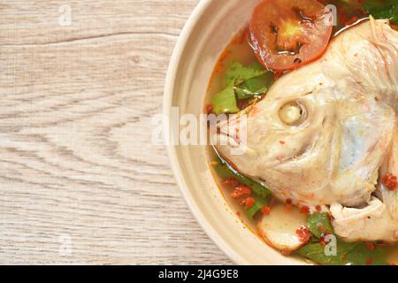 pesce tilapia rosso bollito con pomodoro ed erbe in zuppa di tom yum su ciotola Foto Stock