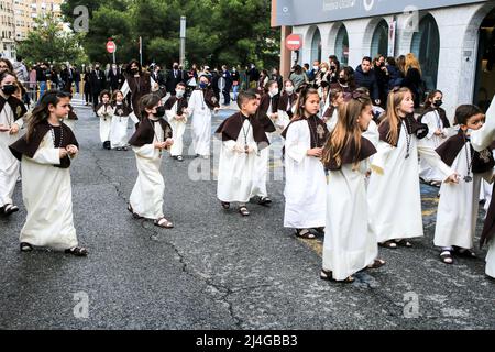 Elche, Spagna - 13 aprile 2022: I bambini in parata pasquale con portieri e penitenti per le strade della città di Elche nella settimana Santa Foto Stock