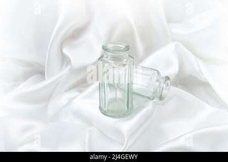 Bottiglie in vetro vintage su sfondo satinato bianco da sogno Foto Stock