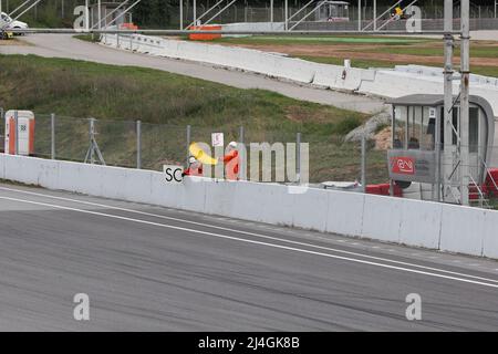 Gara marshall sventolando bandiera gialla durante la gara su pista al Circuit of Catalonia, Barcellona, Spagna Foto Stock