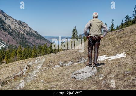 Nelle Alpi bavaresi un escursionista di montagna sorge sul passo di 1129 metri di altezza Spitzingsattel e si affaccia sulla valle fino al lago Schliersee. Foto Stock