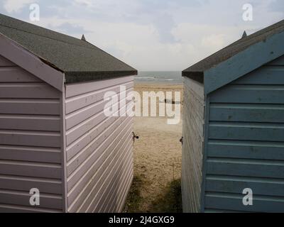 Vista tra due capanne sulla spiaggia di Avon Beach, Christchurch, Dorset, Regno Unito Foto Stock