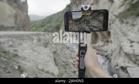 Russia, Kislovodsk - 30 luglio 2021: La donna prende belle viste di montagna al telefono con stabilizzatore. Azione. Scatti professionali al telefono utilizzando Foto Stock