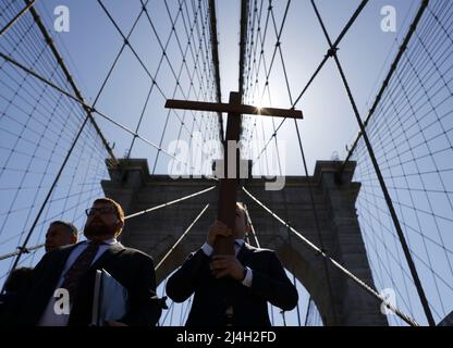 New York, Stati Uniti. 15th Apr 2022. Una croce di legno conduce una processione di centinaia di adoratori sopra il ponte di Brooklyn alla via della Croce evento in celebrazione del Venerdì Santo il 15 aprile 2022 a New York City. La Via Crucis comprende passi evangelici e letture selezionate per contemplare la sofferenza, la morte e la risurrezione di Gesù Cristo che si legano alla domenica di Pasqua. Foto di John Angelillo/UPI Credit: UPI/Alamy Live News Foto Stock