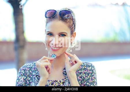 Giovane donna allegra che tiene girocollo arrotondato blu all'aperto Foto Stock