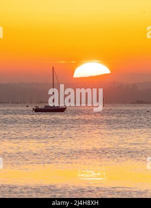 Sandbanks, Poole, Dorset, Regno Unito. 15th aprile 2022. Meteo Regno Unito. Il cielo si illumina di arancione su Poole Harbour a Sandbanks in Dorset durante il tramonto alla fine di una calda giornata di sole il Venerdì Santo. Picture Credit: Graham Hunt/Alamy Live News Foto Stock