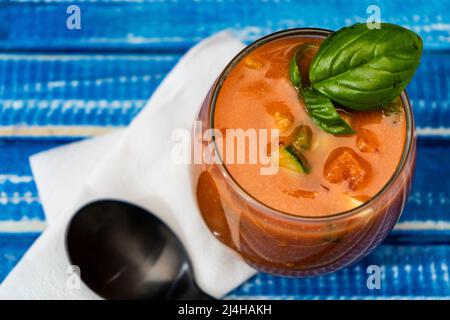 Vista dall'alto di un importante bicchiere con il rinfrescante Gazpacho andaluso su un tavolo di legno blu. Verdura fredda e zuppa organica o bevanda che è bevuto Foto Stock