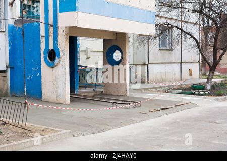 Nuovo edificio di appartamenti con area cieca in cemento. Area cieca recintata con nastro barriera rosso-bianco. Processo di formazione della zona cieca della fondazione, pavimentazioni in calcestruzzo Foto Stock