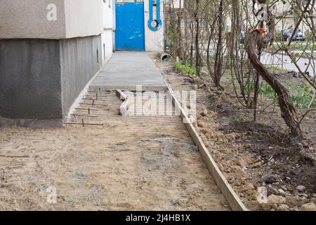 Riparazione della zona cieca nell'edificio dell'appartamento. Preparazione per versare calcestruzzo. L'installazione di un ferro da stiro. Involucro fatto di assi. Foto Stock