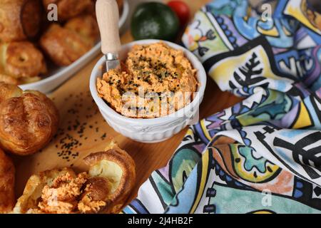 Il popover fatto in casa, che è un rotolo cavo soffiato, arioso ed egoso, è fresco dal forno ed il tuffo della ricotta con i pomodori secchi del sole ed il paprika cotto in un Foto Stock