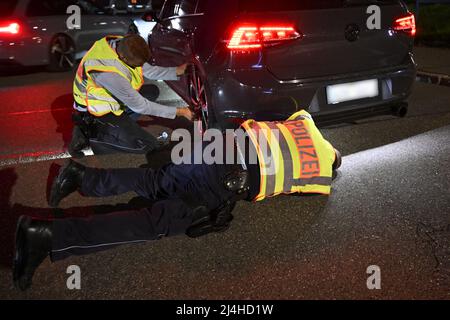 Singen am Hohentwiel, Germania. 15th Apr 2022. Gli ufficiali di polizia controllano un Volkswagen Golf sintonizzato tirato fuori da un controllo del traffico sul cosiddetto Venerdì auto. Tradizionalmente, la scena dei tuner e dei possessori di auto si incontra il Venerdì Santo nella zona di Villingen-Schwenningen e Singen am Hohentwiel. Credit: Felix Kästle/dpa/Alamy Live News Foto Stock