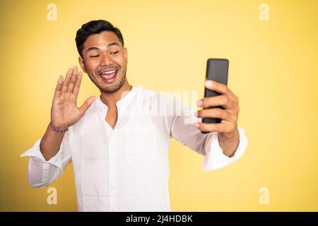 messaggio di saluto di un uomo asiatico durante una videochiamata telefonica utilizzando lo smartphone Foto Stock
