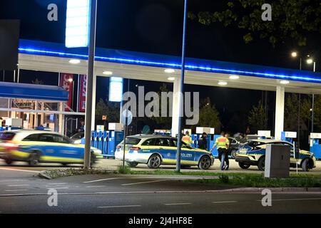 Singen am Hohentwiel, Germania. 15th Apr 2022. Gli agenti di polizia controllano diversi conducenti di auto sintonizzate in una stazione di servizio nella zona industriale. La stazione di servizio è un popolare luogo di incontro per la scena di sintonizzazione sul Car Friday, come i tuner chiamano Venerdì Santo. (Scatto con esposizione lunga) accreditamento: Felix Kästle/dpa/Alamy Live News Foto Stock