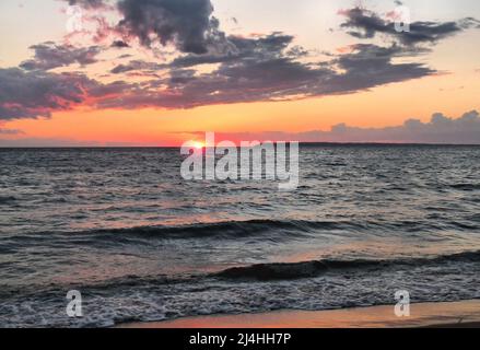 Al tramonto sul lago Michigan, le spettacolari nuvole attraversano un cielo inondato di sfumature di cremisi e oro Foto Stock