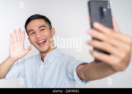 messaggio di saluto di un uomo asiatico durante una videochiamata telefonica utilizzando lo smartphone Foto Stock