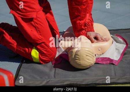 Dettagli con le mani di un operatore dei servizi medici di emergenza che esegue la rianimazione cardiopolmonare (RCP) su un manichino a scopo didattico. Foto Stock