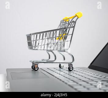 Shopping su Internet. Computer portatile con piccolo carrello sul tavolo,  primo piano Foto stock - Alamy