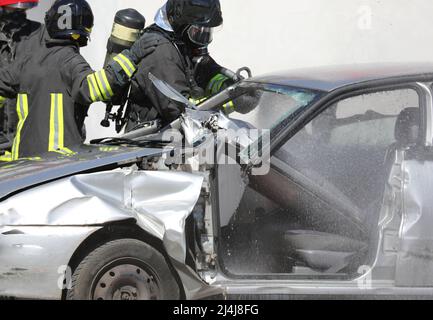 vigili del fuoco con bombola di ossigeno durante il salvataggio della persona gravemente ferita a causa dell'incidente stradale sulla strada Foto Stock