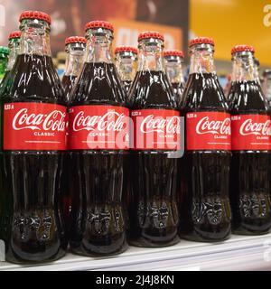 Il lotto di bottiglie di vetro di coca-cola al banco del supermercato. Regione di Mosca, Russia - Aprile 2022. Foto Stock