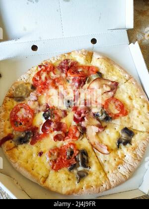 una deliziosa pizza in una scatola sul tavolo Foto Stock