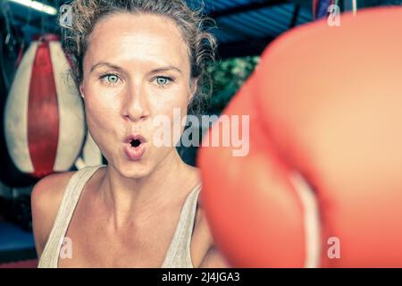 Donna di colpire con un punzone sulla determinazione spietata - Fitness boxe e mixed martial arts concetto - Montare la ragazza sulla difesa di auto tecnica in una schifezza combattere c Foto Stock