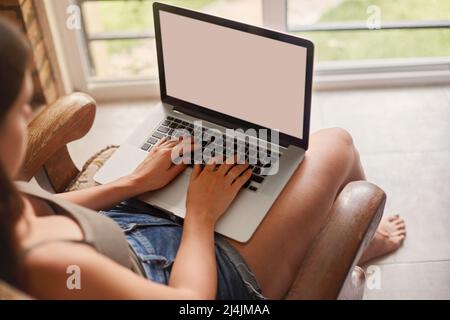 Donna che lavora su un notebook. Donna che utilizza un notebook per la ricerca sul Web, la navigazione delle informazioni e l'uso del posto di lavoro a casa. Foto Stock