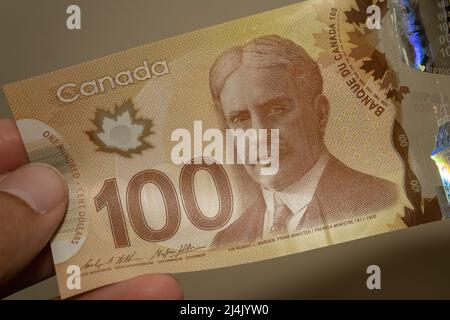 Le persone che danno la valuta del Canada - un bruno cento dollari banconote sparse su uno sfondo marrone. Cambio valuta. Foto Stock