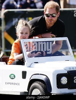 Il Duca del Sussex è guidato da un bambino in un giocattolo Land Rover alla Jaguar Land Rover Driving Challenge durante gli Invictus Games a Zuiderpark l'Aia, Paesi Bassi. Data foto: Sabato 16 aprile 2022. Foto Stock