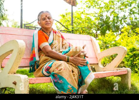 Donna anziana che soffre di dolore alle articolazioni kee dopo aver camminato mentre si siede al parco - concetto di artrite, malsano e malattia Foto Stock