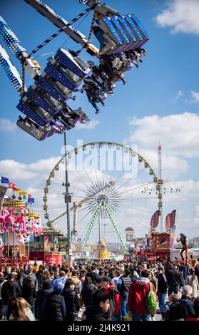 16 aprile 2022, Baden-Wuerttemberg, Stoccarda: Numerosi visitatori attraversano il Cannstatter Wasen durante il Festival primaverile di Stoccarda 82nd. Dopo una pausa di due anni a causa della corona, la festa di primavera ritorna come una "versione leggera". Foto: Christoph Schmidt/dpa Foto Stock